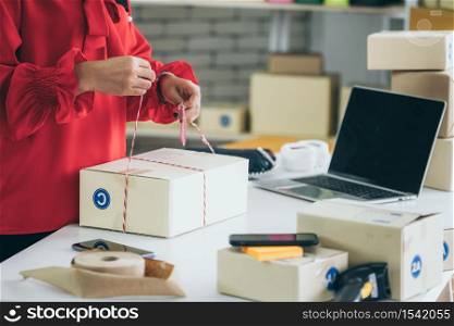 Online seller works at home office and packs shipping delivery box to customer. Small business owner or entrepreneur doing e-commerce business on the internet.