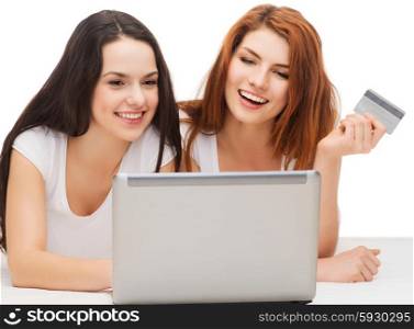 online shopping and technology concept - two smiling teenage girls with laptop computer and credit card. two smiling teenagers with laptop and credit card