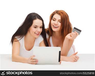 online shopping and technology concept - two smiling teenage girls with tablet pc computer and credit card