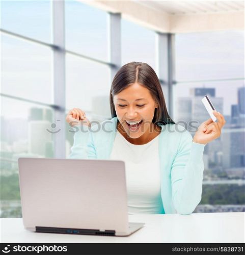 online shopping, banking, business and people concept - happy businesswoman with laptop and credit card over office window background