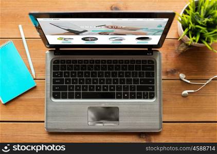 online shopping, business and technology concept - close up of laptop computer with internet shop web page on screen wooden table