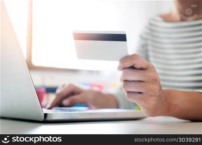 Online shopping concept. hand of happy young holding smartphone and pays for a purchase with credit card with laptop.. Online shopping concept. hand of happy young holding smartphone