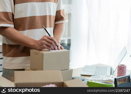 Online shopping concept the seller writing his customer&rsquo;s address on the parcel and being ready for sending it.