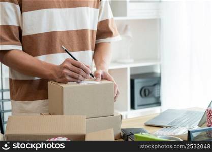 Online shopping concept the seller writing his customer&rsquo;s address on the parcel and being ready for sending it.