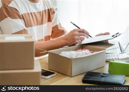 Online shopping concept the selling agent writing down a product report and checking his product in the parcel.