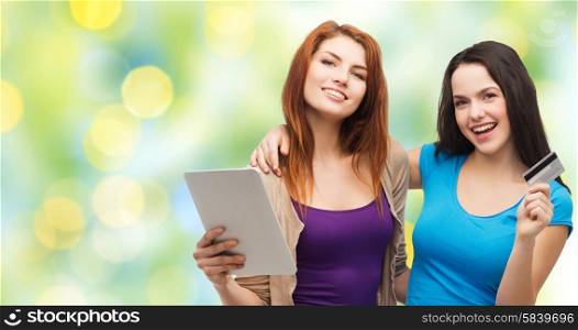 online shopping, e-money, commerce, people and technology concept - two smiling teenage girls or young women with tablet pc computer and credit card over green lights background