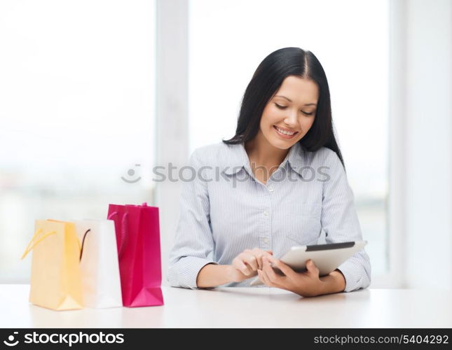 online shopping, electronics and gadget concept - smiling woman with blank screen tablet pc and shopping bags