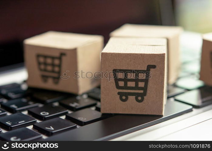 Online shopping - Paper cartons or parcel with a shopping cart logo on a laptop keyboard. Shopping service on The online web and offers home delivery.