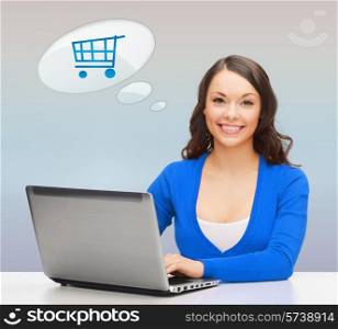 online shopping, people and technology concept - smiling young woman with laptop computer over gray background and trolley