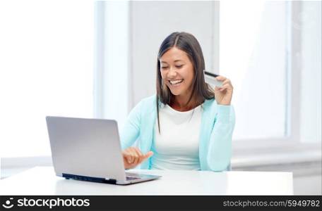 online shopping, people and technology concept - smiling young woman with laptop computer and credit card at home or office