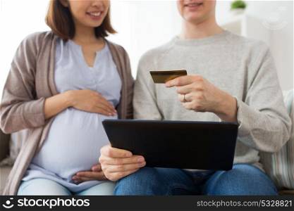 online shopping, pregnancy and people concept - close up of happy man and his pregnant wife with tablet pc computer and credit card at home. close up of man and pregnant wife shopping online
