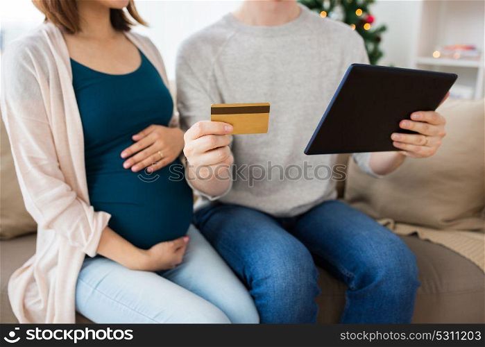 online shopping, pregnancy and people concept - close up of man and his pregnant wife with tablet pc computer and credit card at home. close up of man with pregnant wife shopping online