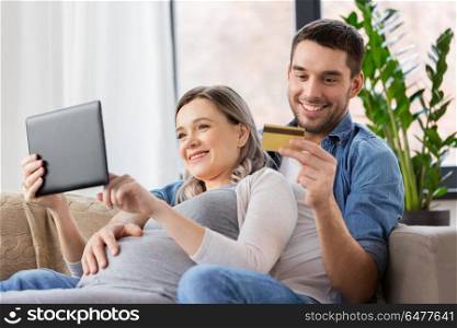 online shopping, pregnancy and technology concept - happy man and his pregnant wife with tablet pc computer and credit card at home. man and pregnant wife shopping online at home. man and pregnant wife shopping online at home