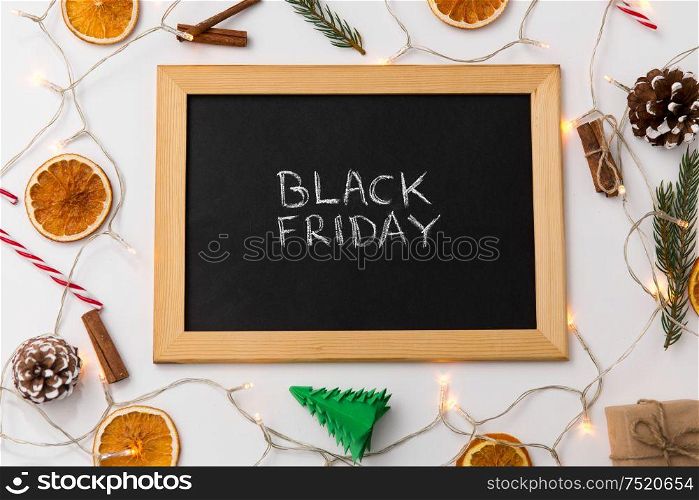 online shopping, sale and marketing concept - black chalk board with black friday words and christmas decorations on table. chalk board with black friday words on christmas