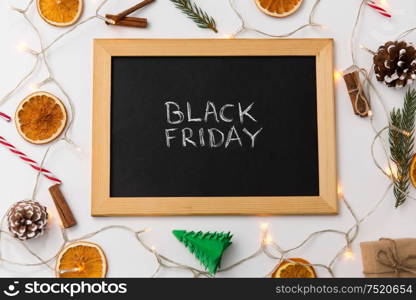 online shopping, sale and marketing concept - black chalk board with black friday words and christmas decorations on table. chalk board with black friday words on christmas