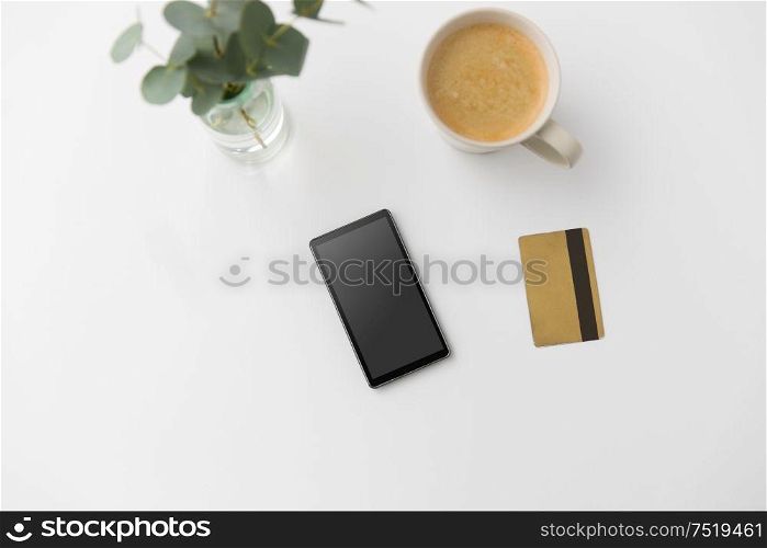 online shopping, sale and technology concept - smartphone, credit card and cup of coffee on white background. smartphone, credit card and cup of coffee