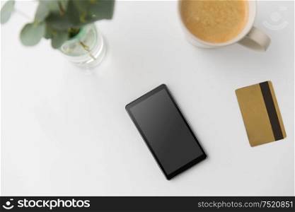online shopping, sale and technology concept -smartphone, credit card and cup of coffee on white background. smartphone, credit card and cup of coffee