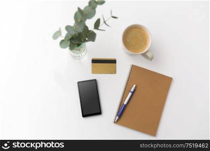 online shopping, sale and technology concept -smartphone, credit card, notebook and cup of coffee on white background. smartphone, credit card, notebook and coffee