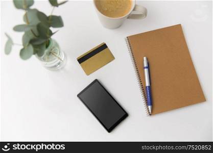 online shopping, sale and technology concept -smartphone, credit card, notebook and cup of coffee on white background. smartphone, credit card, notebook and coffee