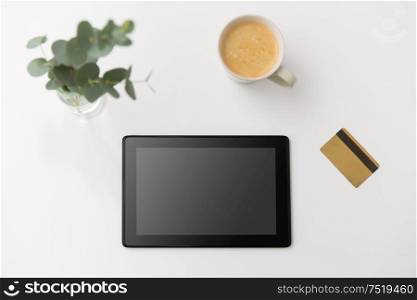 online shopping, sale and technology concept - tablet pc computer, credit card and cup of coffee on white background. tablet pc computer, credit card and cup of coffee