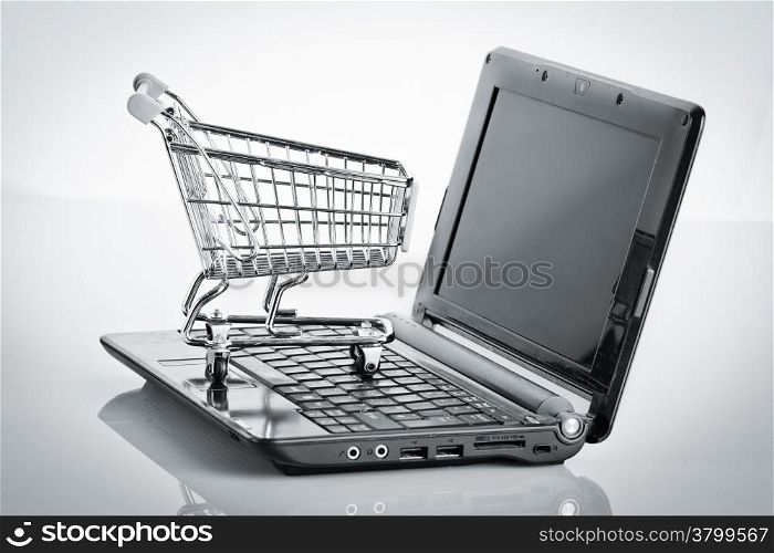 Online shopping. Shopping cart with notebook on the white. shopping cart over a laptop