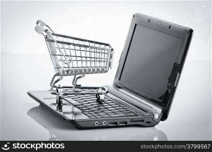 Online shopping. Shopping cart with notebook on the white. shopping cart over a laptop