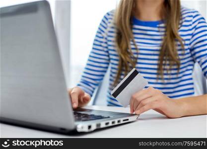 online shopping, technology and people concept - teenage girl with laptop computer and credit card at home. teenage girl with laptop and credit card at home