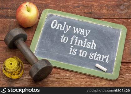 Only way to finish is to start - motivational slate blackboard sign against weathered red painted barn wood with a dumbbell, apple and tape measure