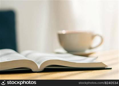 open bible with white cup of coffee with the morning atmosphere on a wooden table near the window sill