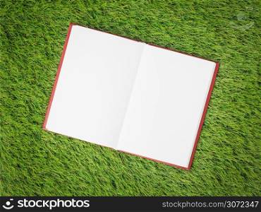open blank book on artificial green grass
