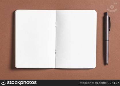 open blank book with pen brown background