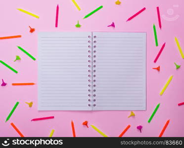 open blank notebook in a line in the middle of a candle for a festive cake on a pink background