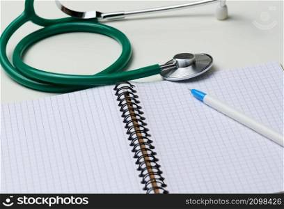 open blank notebook with pen and stethoscope, white table