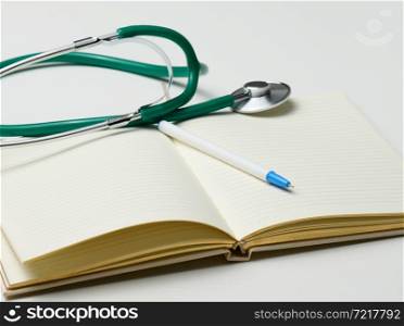 open blank notebook with pen and stethoscope, white table
