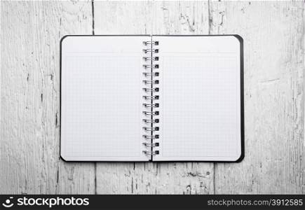 Open blank notepad with empty white pages laying on a wooden table