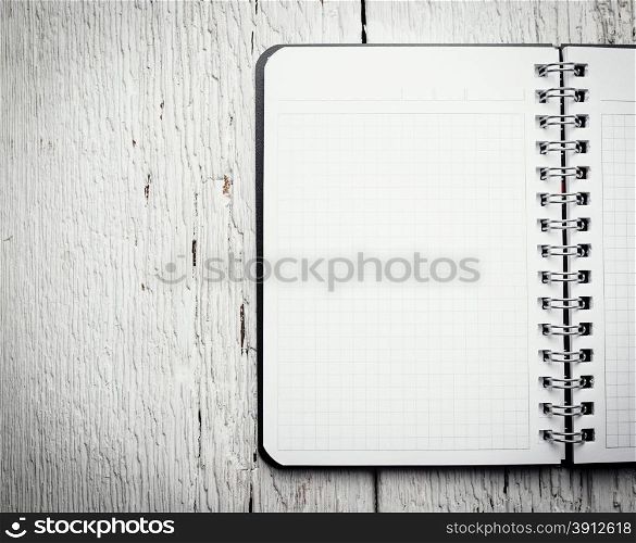 Open blank notepad with empty white pages laying on a wooden table