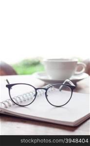 Open blank white notebook and eyeglasses with cup of coffee, stock photo