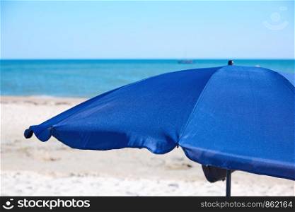 open blue textile beach umbrella on a sandy seashore, vacation concept