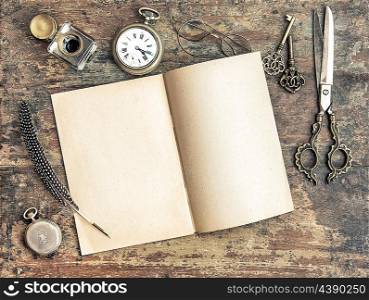 Open book and antique writing tools on wooden background. Vintage style toned picture