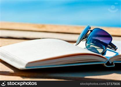 open book and sunglasses on the background of the sea