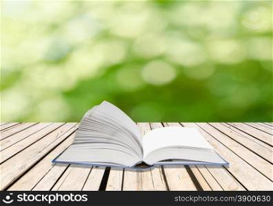 Open book on wood floor with green background&#xA;