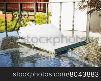 Open book outdoor, over glass reflecting table, horizontal image