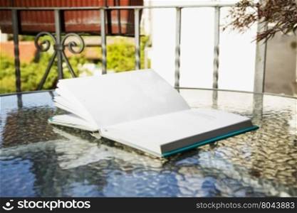 Open book outdoor, over glass reflecting table, horizontal image