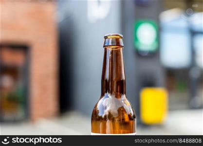 open brown glass bottle close up outdoors in summer evening