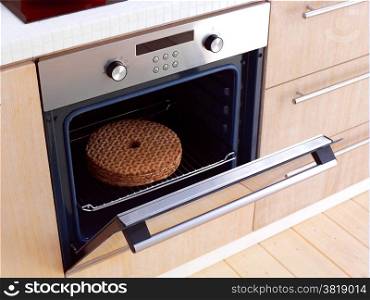 Open built-in electric oven with French fries and stainless steel cooking pots on stove