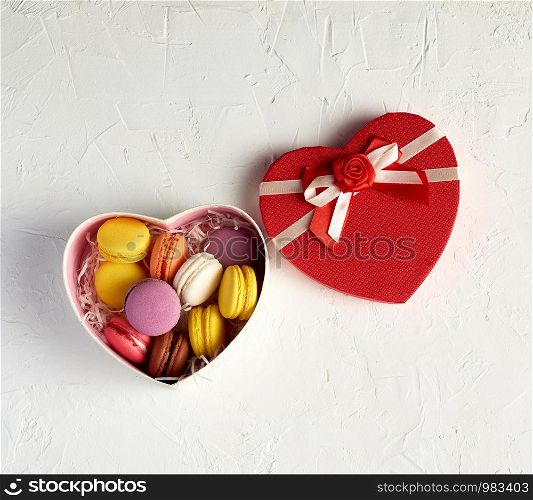 open cardboard box with a baked dessert multi-colored round macarons, top view, white background