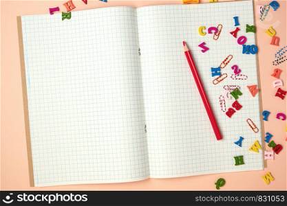open checked notebook and red wooden pencil, back to school backdrop