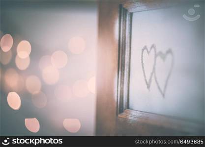 Open doors to love, two handwriting hearts on the open door, festive blurry bokeh lights behind, conceptual photo of first affection or true love. Open doors to love