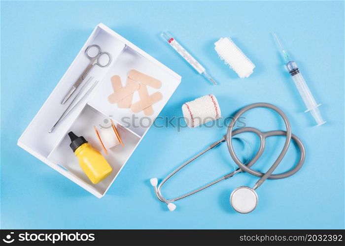 open first aid kit with medical equipments blue background