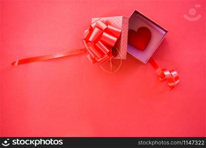 Open Gift Box and red heart in box surprise / red present box with ribbon bow for gift to Merry Christmas Holiday Happy new year or Valentines day on red background copy space top view